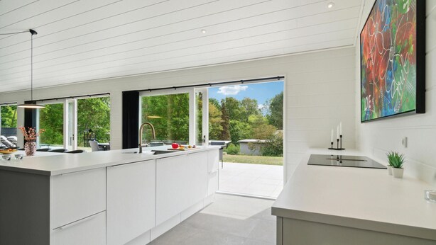Una cocina moderna con armarios blancos, una isla grande y vistas al exterior.