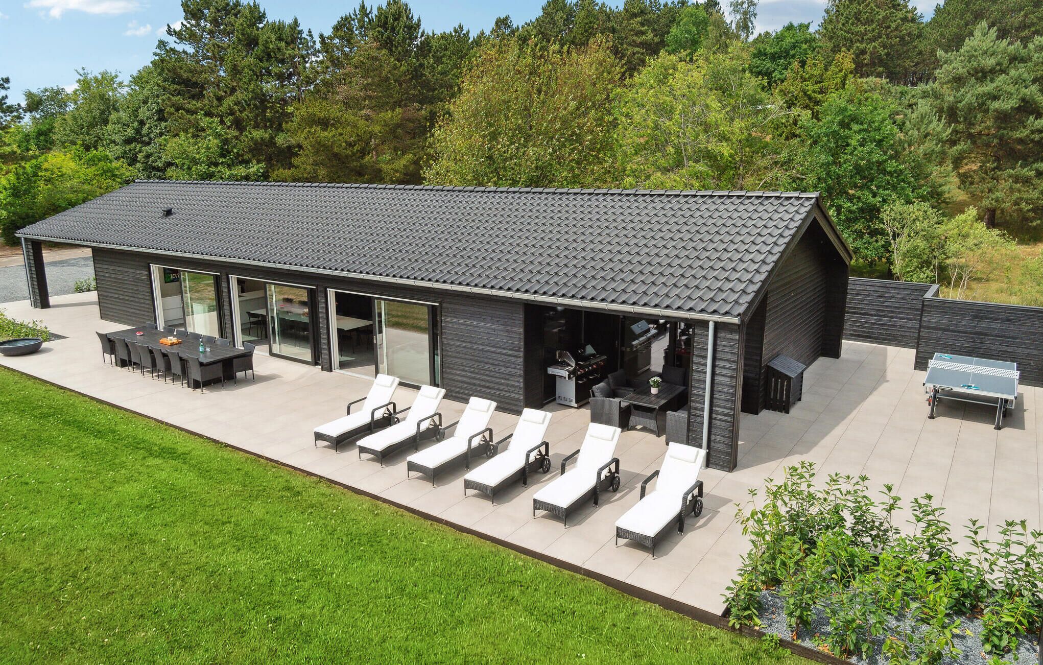 Et moderne hus med en patio, udendørs møbler og grillområde.