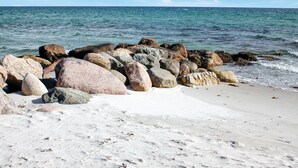 Una playa con rocas grandes y una orilla arenosa.