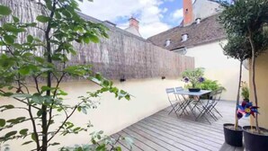 A wooden deck with a table and chairs, surrounded by potted plants and a tree. - The heart of Fontainebleau (Fontainebleau)