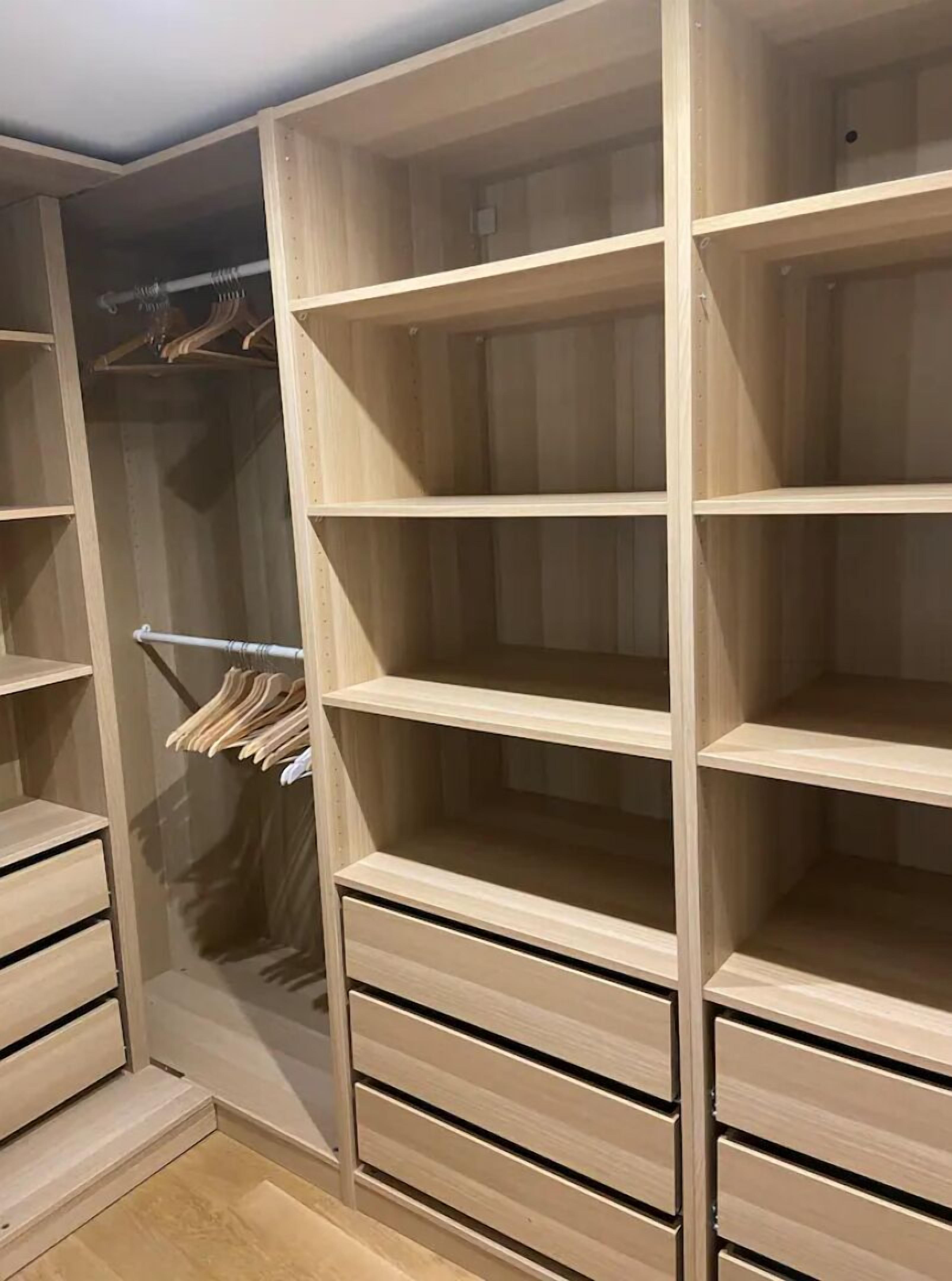 Een houten kast met meerdere planken en lades, een kledingroede en een spiegeldeur.