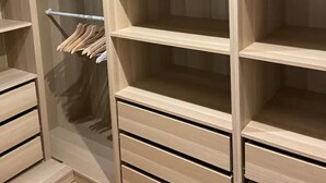 A wooden closet with multiple shelves and drawers, a hanging rod, and a mirrored closet door. - The heart of Fontainebleau (Fontainebleau)