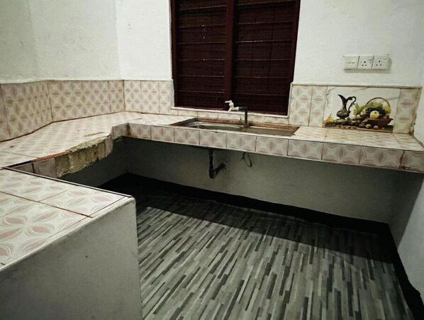 A compact kitchen with a sink, a window with a wooden shutter, and a patterned backsplash.