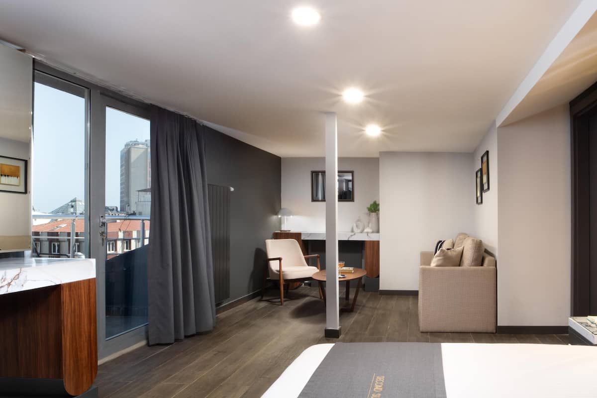 Moderni hotellihuone, jossa on suuri ikkuna, työpöytä, sohva ja pieni pöytä.