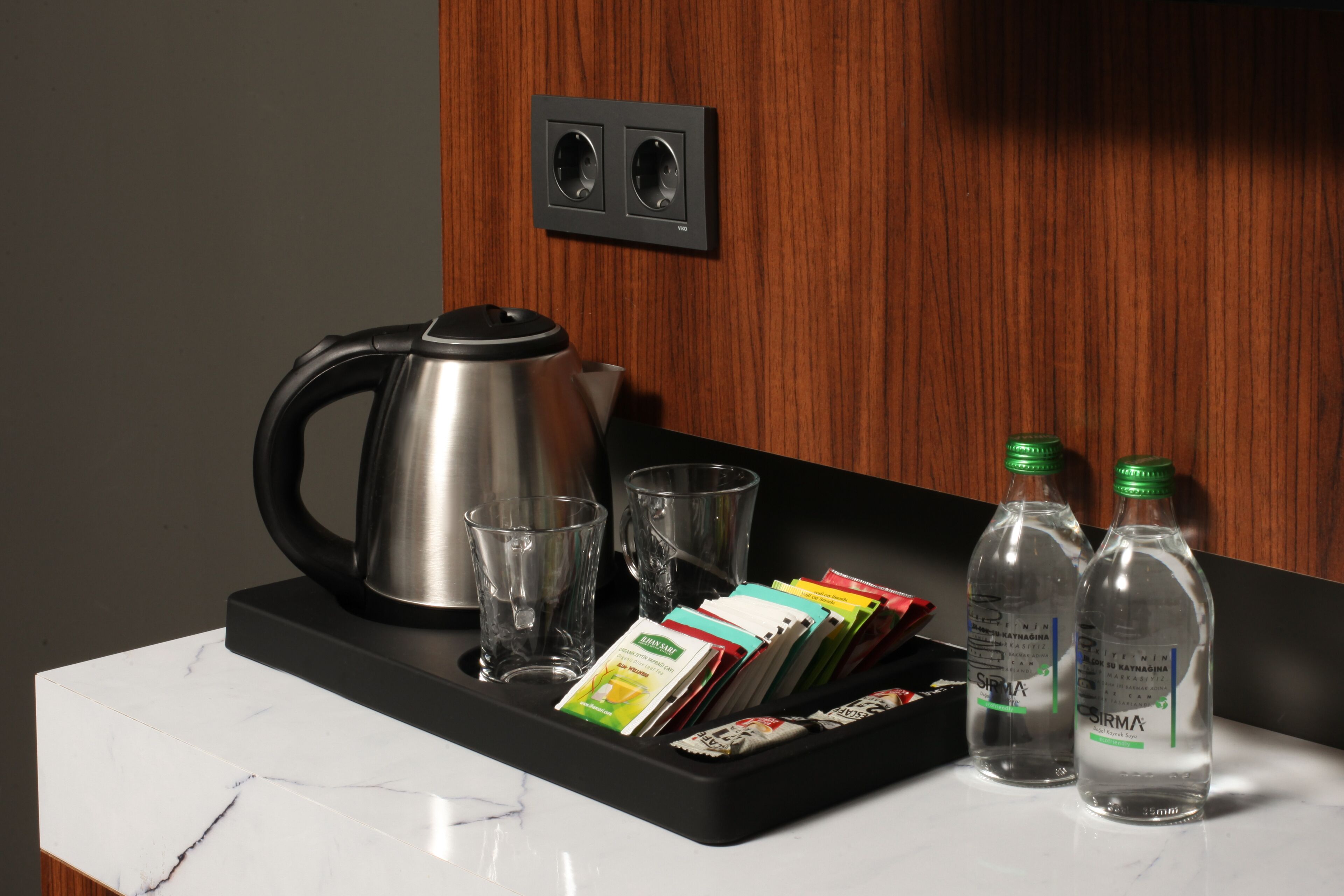 A kitchen counter with a kettle, glasses, and bottled water.