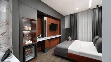 A modern hotel room with a bed, a built-in TV, a minibar, and a bathroom with a marble wall.