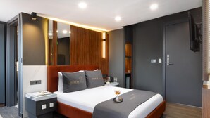 Una habitación de hotel moderna con una cama grande, mesitas de noche, un espejo y un televisor.
