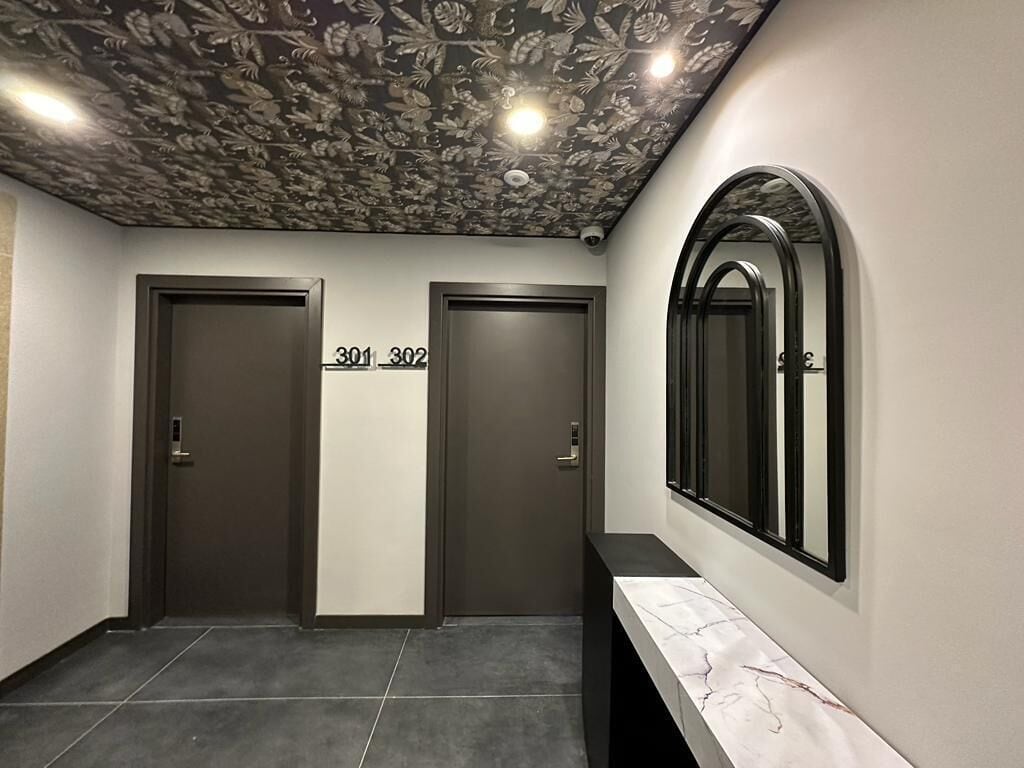 A hallway with two doors labeled 301 and 302, a marble-tiled floor, and a ceiling with a floral pattern.
