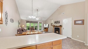 A spacious kitchen with a large island, wooden cabinets, a fireplace, and a dining area with a sofa and table. - Golf Condo + Connecting Suite at StoneBridge Resort (Reeds Spring)