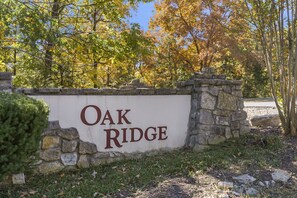 Een bord met de tekst 'Oak Ridge', met een stenen muur en bomen op de achtergrond.