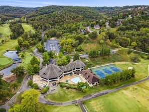 Un campo de golf con un club, piscina y canchas de tenis.