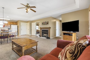 A spacious living room with a fireplace, a television, and a ceiling fan.
