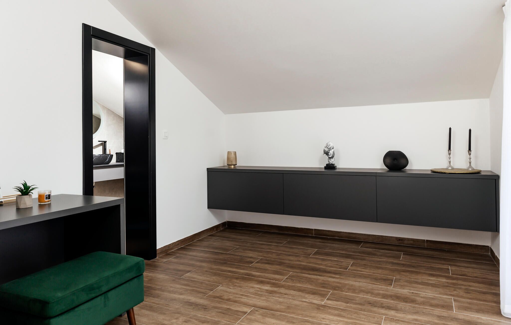 Ein modernes Wohnzimmer mit einer dunkelgrauen Konsole, einer grünen Bank und Holzboden.