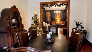 A dining room with a wooden table, chairs, a Christmas tree, and a chandelier. - Spacious Historic Home: 4 bedrooms, 2.5 bath (New Oxford)