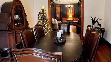 Une salle à manger avec une table en bois, des chaises, un sapin de Noël et un lustre.