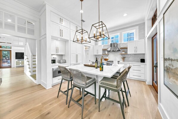 A spacious kitchen with white cabinetry, a central island, and bar stools.