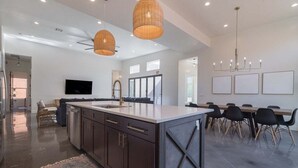 A modern kitchen with dark cabinetry, a central island, and pendant lighting.
