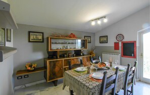 Une salle à manger avec une table dressée pour quatre personnes, un buffet en bois doté de portes en verre et un radiateur fixé au mur.