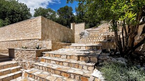Escalones de piedra que conducen a un muro de piedra con una pequeña estatua en la parte superior.