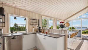 Een moderne keuken met witte kasten, een Bosch vaatwasser en een groot raam met uitzicht op een mooi landschap.