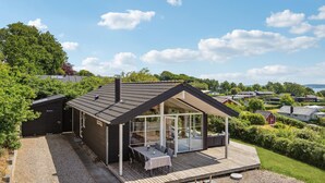 Een modern huis met een ruim terras, een overdekte patio en uitzicht op een weelderig groen landschap.