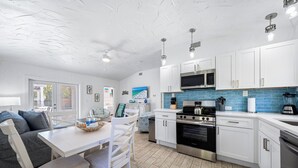 Une cuisine moderne avec des armoires blanches, des appareils en acier inoxydable et un pare-feu bleu.