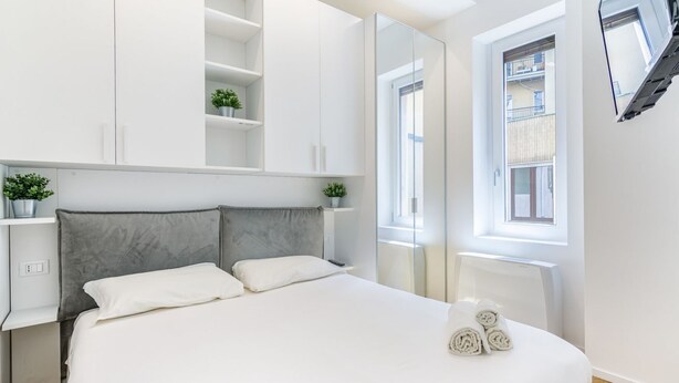 Ein modernes Schlafzimmer mit einem großen Bett, Einbauschränken, einem Fenster mit Blick und einem Spiegel.