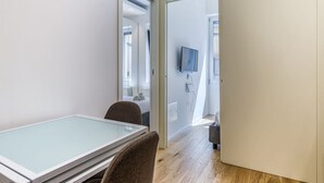 Ein modernes Zimmer mit einem Glastisch, einer Couch und einem an der Wand befestigten Fernseher.