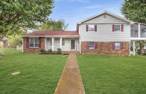 Stunning two-story house with a central entrance, covered porch, and two windows with shutters.