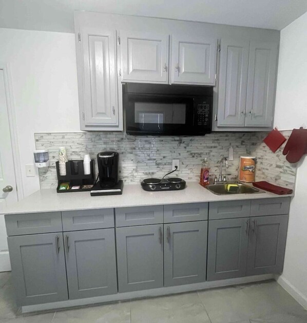Compact kitchen with modern design, featuring a microwave oven, coffee maker, and rice cooker.