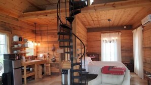 A cozy cabin interior with a spiral staircase, a dining area, a bed, and a kitchenette. - Your 15 acres of privacy on the water- Rock Island (Rock Island)