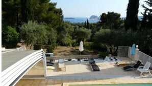 A poolside area with lounge chairs and a view of the sea.