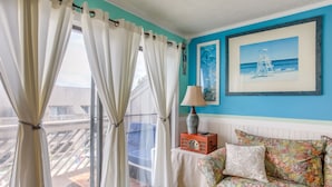 A room with a view of a balcony, a sofa with floral upholstery, and a framed picture on the wall. - Private Pool-View Balcony: Myrtle Beach Condo! (Myrtle Beach)