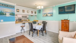A dining area with a table and chairs, a kitchen in the background, and a TV mounted on the wall. - Private Pool-View Balcony: Myrtle Beach Condo! (Myrtle Beach)