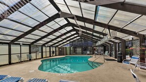 An indoor swimming pool with clear glass ceilings, lounge chairs, and safety signs. - Private Pool-View Balcony: Myrtle Beach Condo! (Myrtle Beach)
