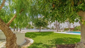 Un parque con piscina, árboles y césped cuidado.