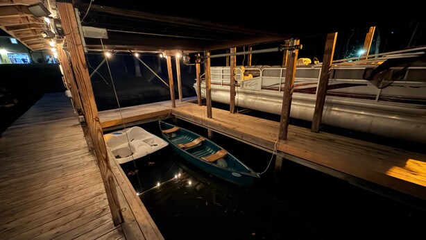 Une jetée en bois avec une petite embarcation et un espace abrité doté d’une rambarde en métal.