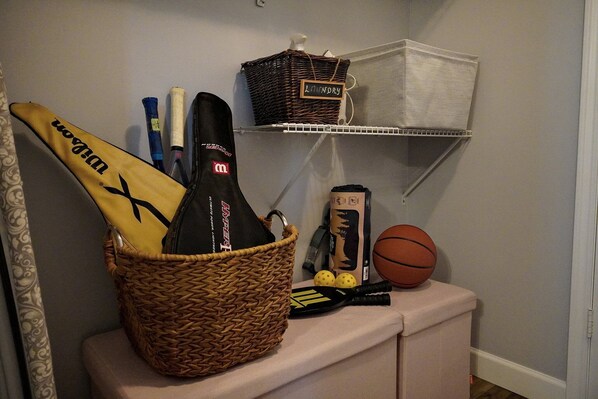 A basket with sports equipment, a bottle, and a box on a shelf.