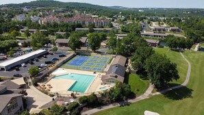 Ett flygbildsfoto av ett bostadsområde med en stor swimmingpool, tennisbanor och en golfbana.