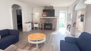 A modern living room with a stone fireplace, two sofas, a coffee table, and a television. - Crystal Beach Getaway (Fort Erie)