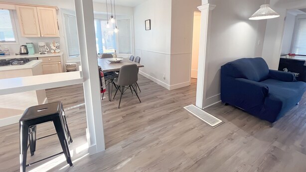 A modern living space with a dining area, a blue sofa, and a kitchen visible through an archway. - Crystal Beach Getaway (Fort Erie)