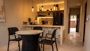 Een moderne keuken met een centraal eiland, hanglampen en uitzicht op een eetgedeelte met een ronde tafel en stoelen.