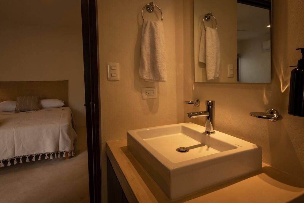 Un baño de hotel con un lavamanos blanco, un espejo y una toalla colgada en un aro.