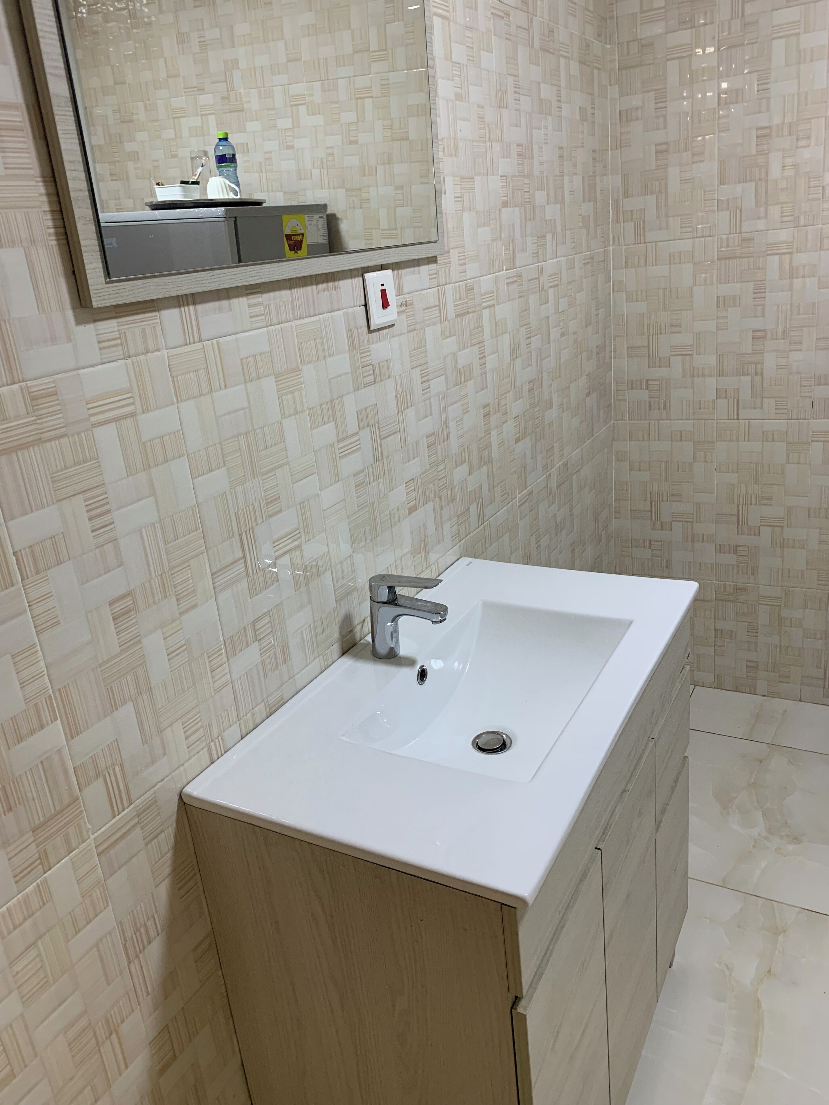 A bathroom with a white sink, a mirror above it, and a patterned wall.