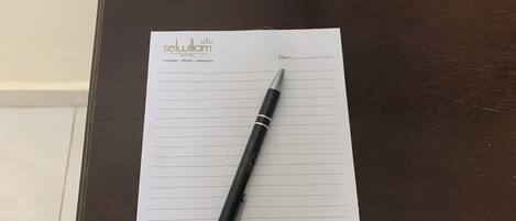A hotel reception desk with a notepad, pen, and a small vase with flowers.