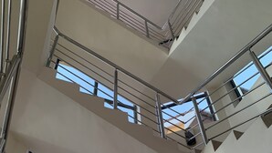 Interior de varios niveles con barandillas metálicas y ventanas amplias que dejan entrar luz natural.