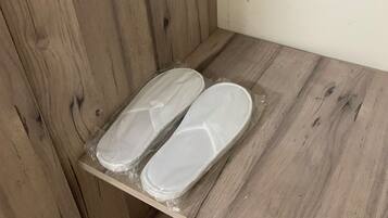 Un plancher en bois sur lequel se trouve une étagère avec deux paires de chaussons blancs.