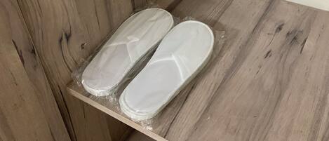 A wooden floor with a shelf holding two white slippers.