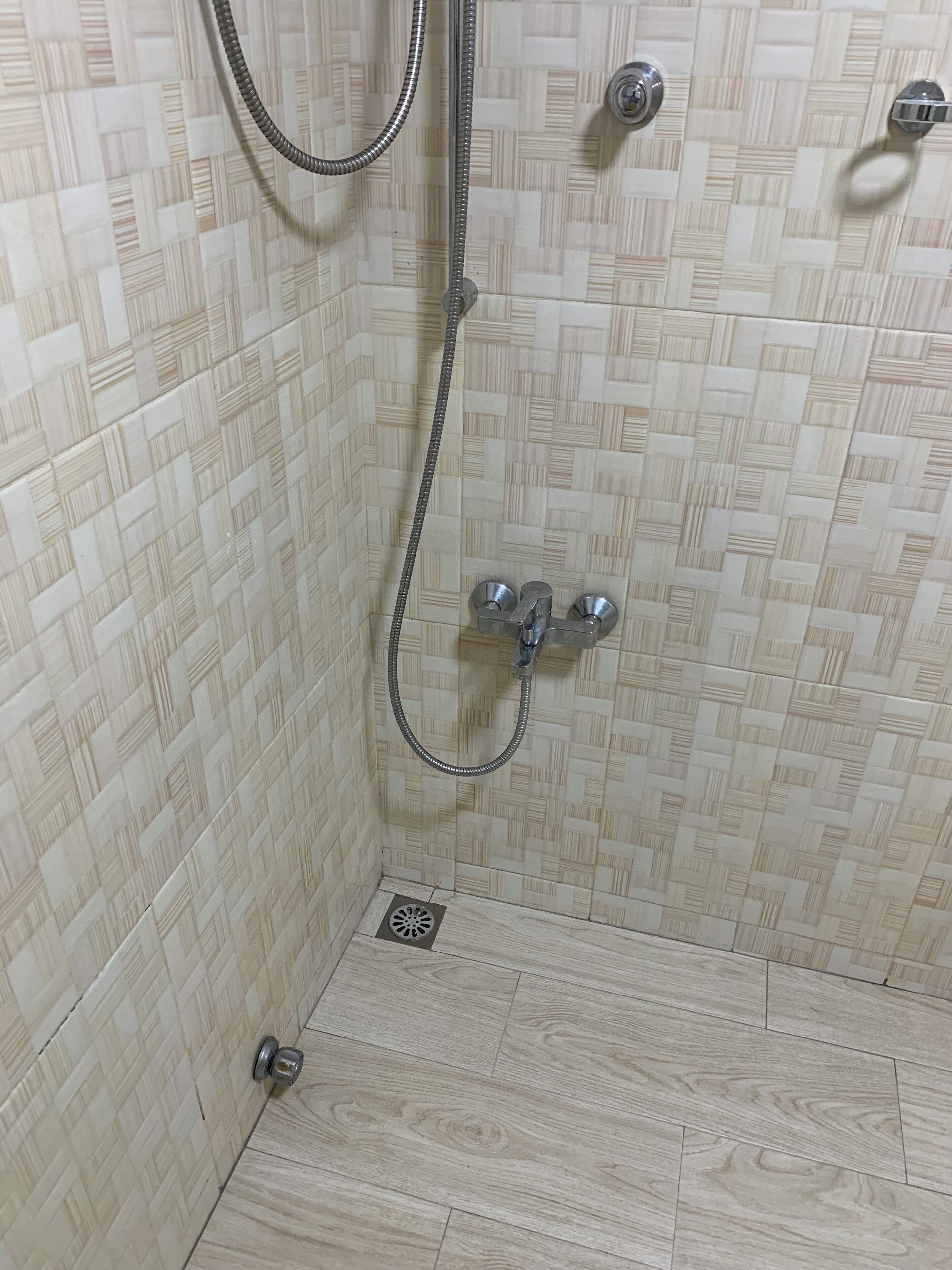A shower area with a tiled wall, a showerhead, and a control panel.