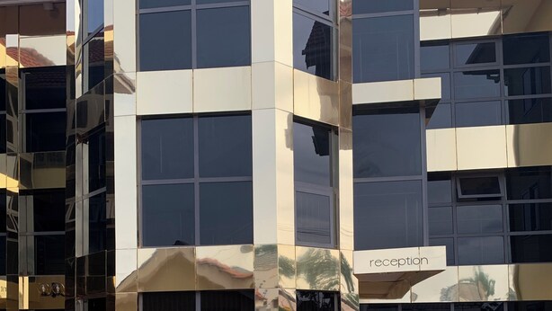 Un edificio moderno con una recepción, ventanas amplias y plantas en macetas.